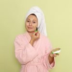 Mulher de roupão rosa fazendo skincare